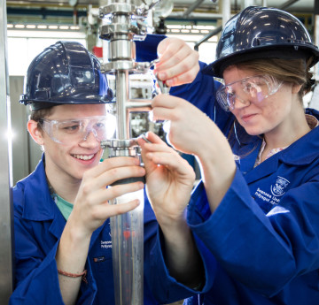 Two engineering students conducting an experiment with overalls and googles. 