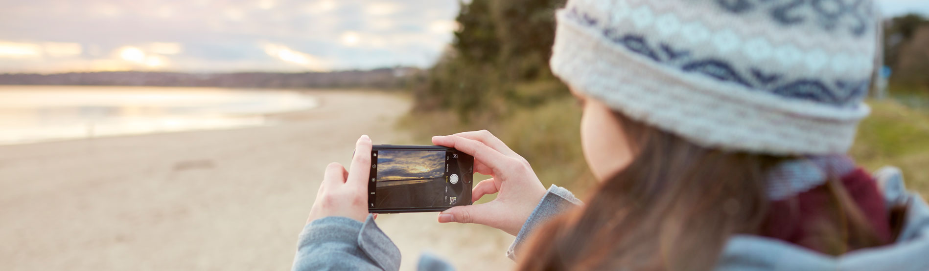 Student taking a photo on a beach