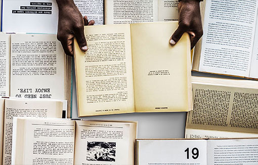 A man reading a book surrounded by books