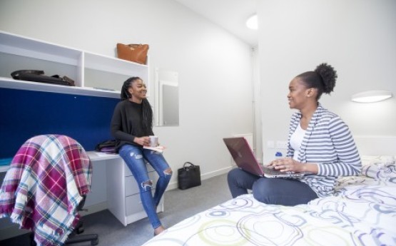 Two female students chatting in a bedroom