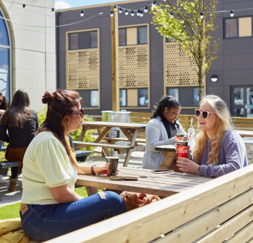 two female students sat on a bench outside Tafan Tawe