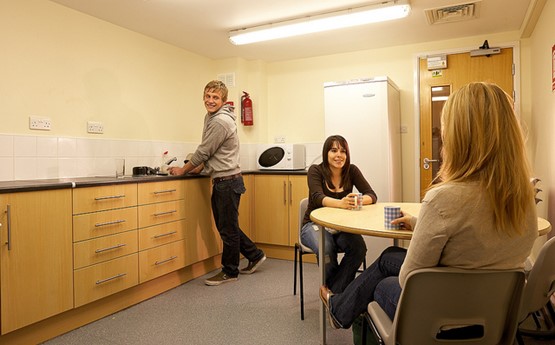 three students in a kitchen