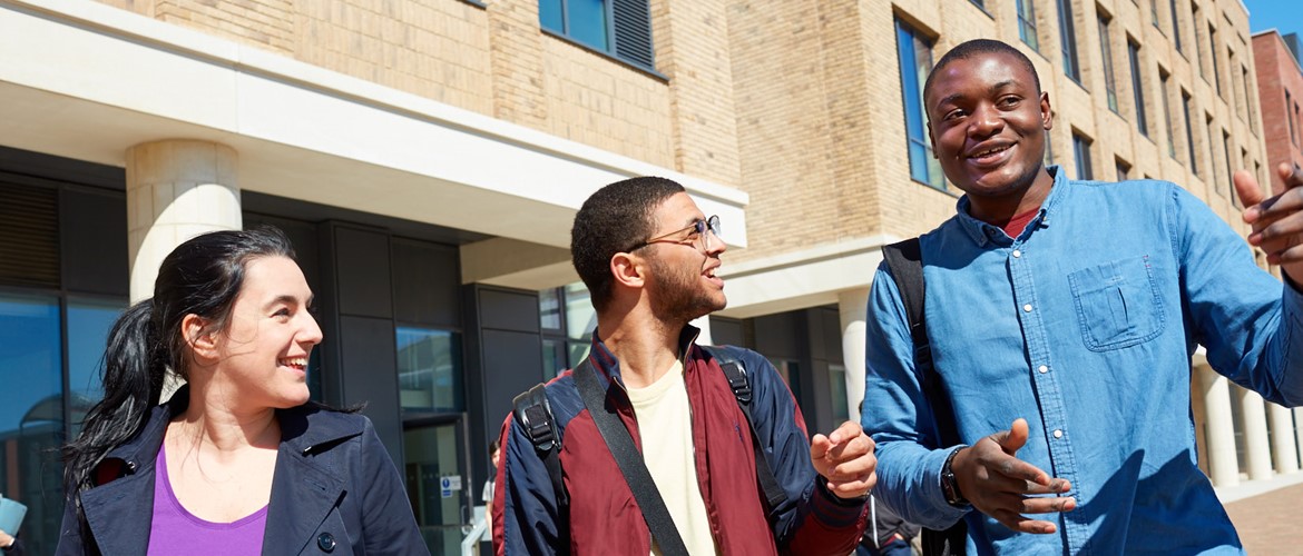 A group of three students walking on Bay Campus