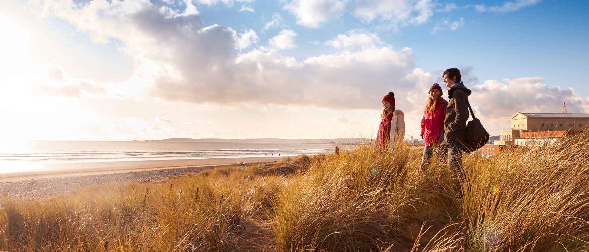 A group of three students looking at the beach