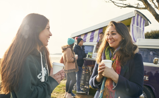 two girls having coffee at the beach front