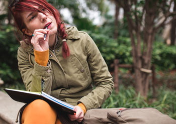 female student thinking while writing