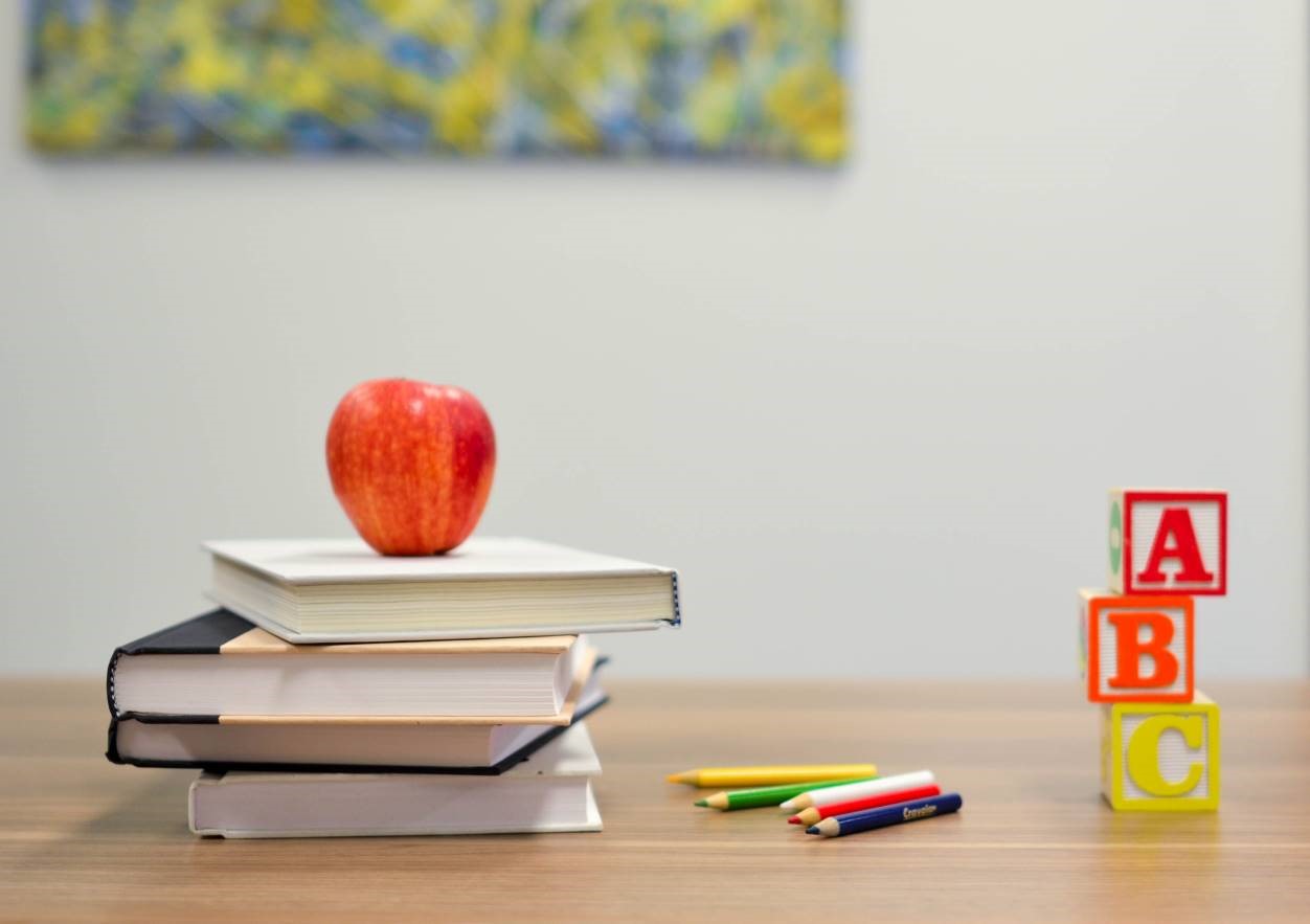 Image of a pile of books and an apple. 