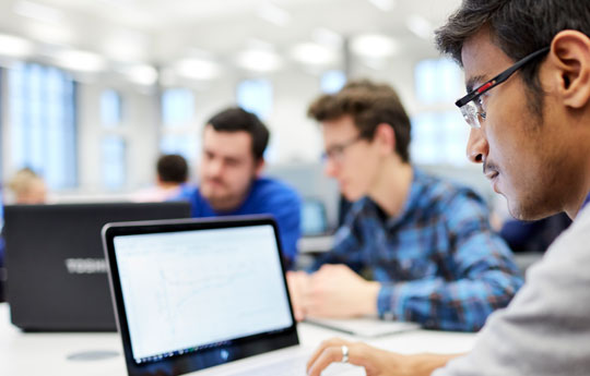 Postgraduate students studying on a laptop