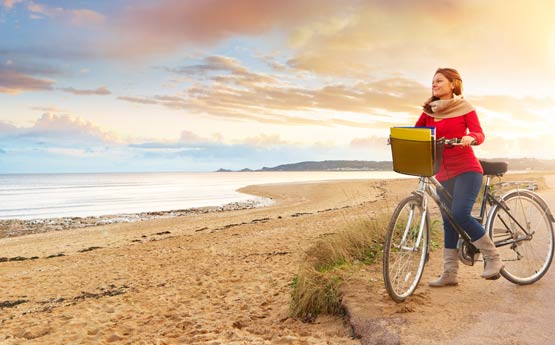 Student on a bike at the beach looking at the view of mumbles at dusk