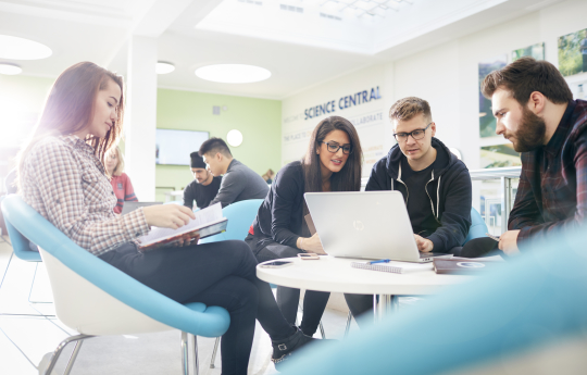 Students working together around a laptop