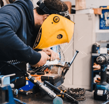 A student in a safety helmet working on metal