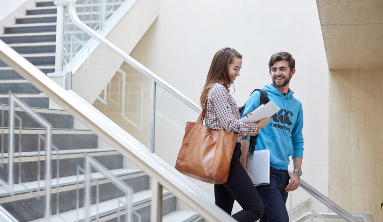 Two students talking in seating area.