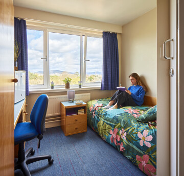 Female student in halls of residence, sitting on the bed