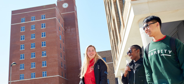 Three students walking across Bay Campus 