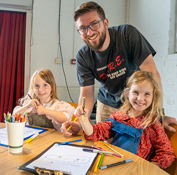 Father and two daughters sat at table creating