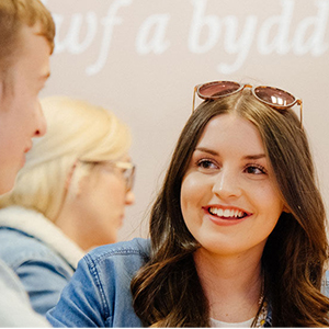 image of students chatting in front of wall displaying Welsh text