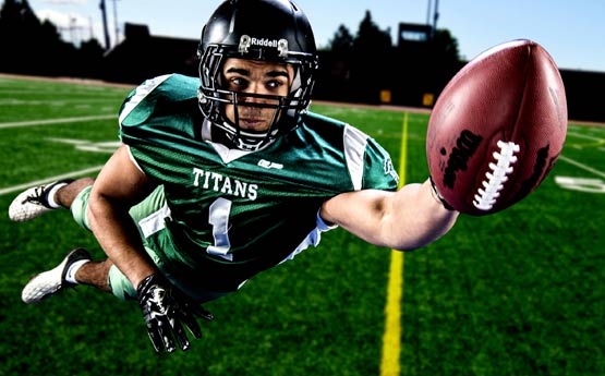 American football player diving to catch a ball in mid-air