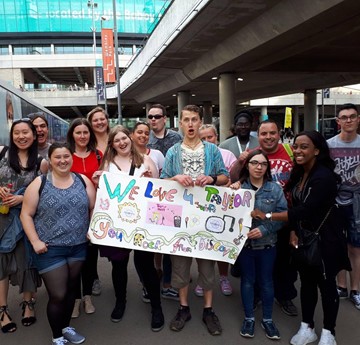 A group of Discovery Volunteers at a train station holding a sign that reads 