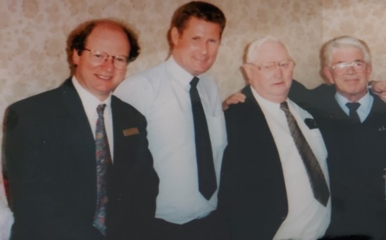 Geraint and 3 male colleagues stand in a row smiling for the camera 