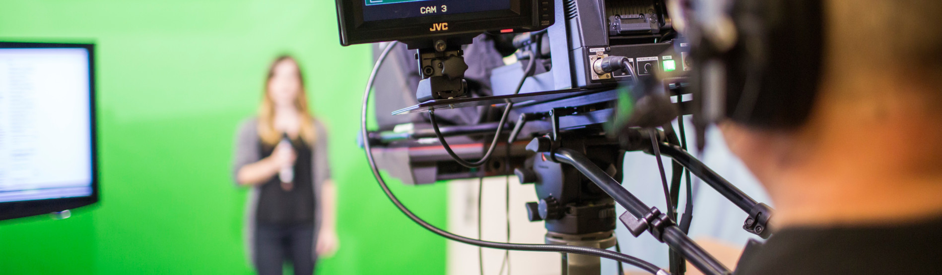 Camera facing a person in front of a green screen. 