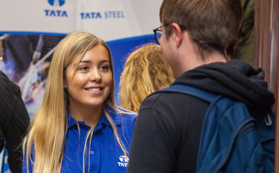 Woman wearing Tata Steel polo shirt speaking to a man