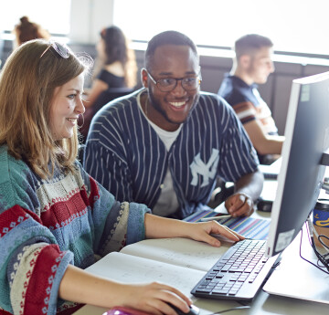 Two students (one female and one male) sitting infron of a PC screen