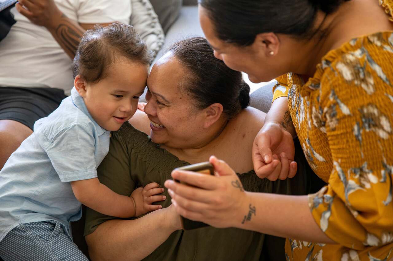 Women showing child something on phone.