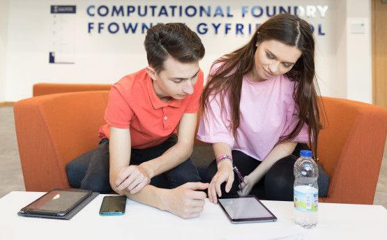 Students looking at an iPad in the Computational Foundry seating area