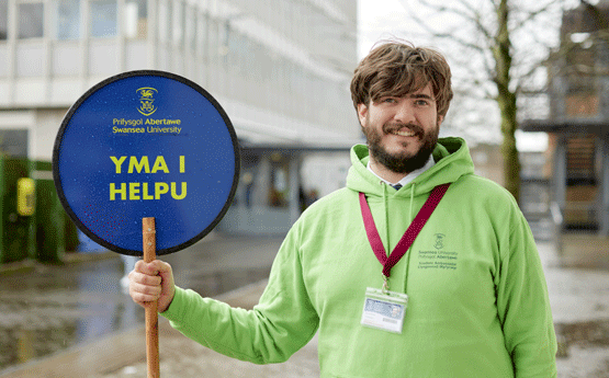 Student holding 'Here to Help' sign