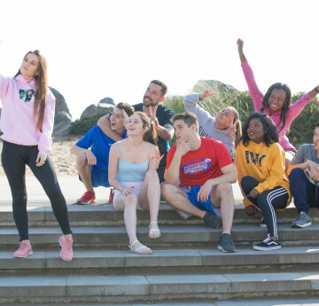 Students sitting on steps by beach taking a photo