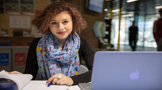 Girl working on a laptop smiling at camera