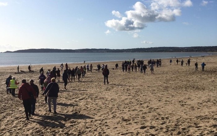 Y Brifysgol yn croesawu dychweliad taith gerdded elusennol ar y traeth