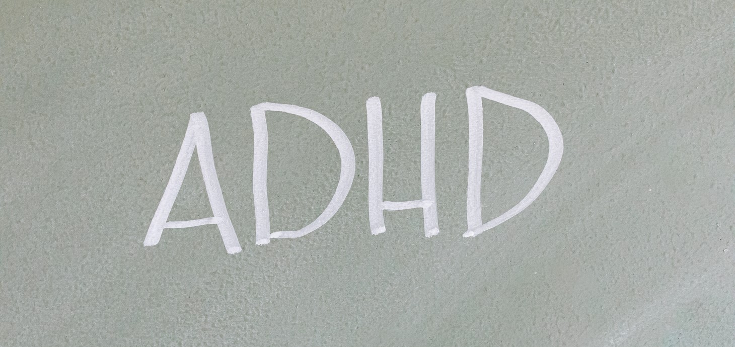 Bwrdd du â'r acronym ADHD wedi'i ysgrifennu arno mewn sialc.