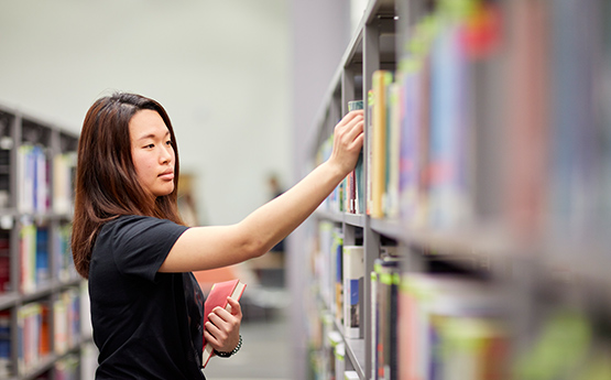 Student reading book in library.