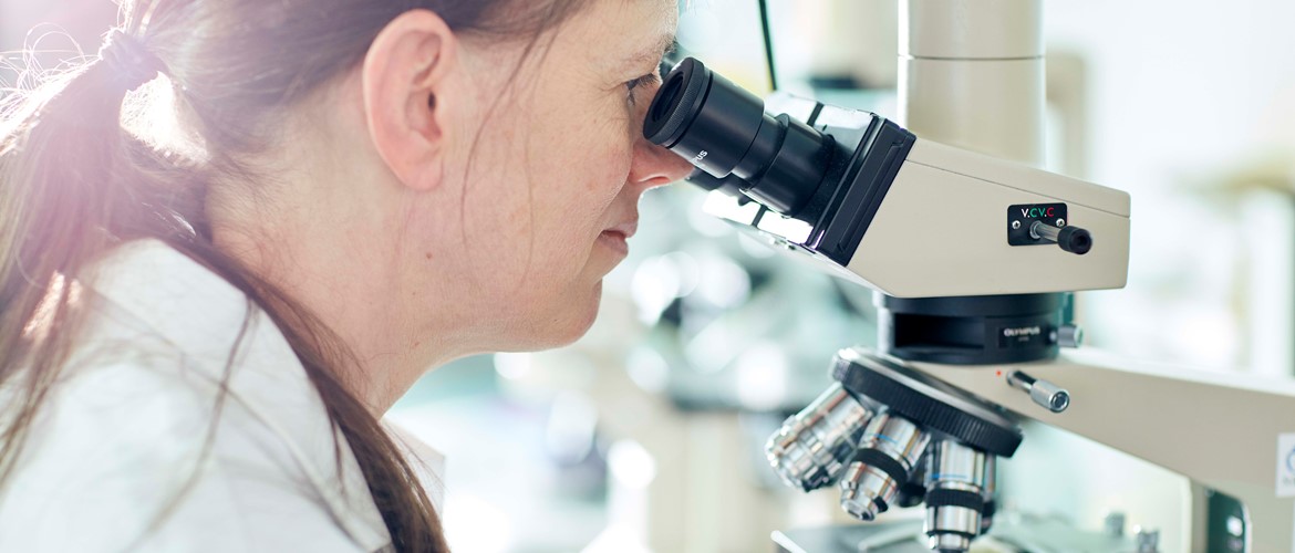 a researcher looking through a microscope 