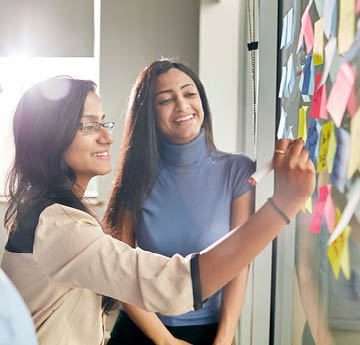 two women writing on post it notes