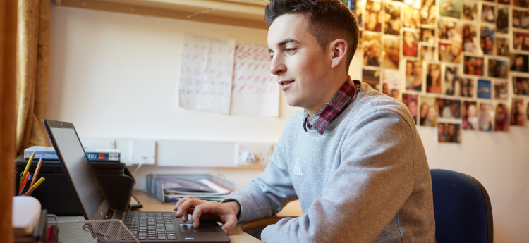 student typing on laptop