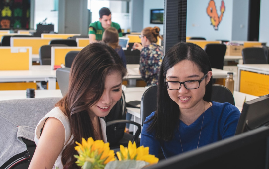 Chinese students smiling at laptop