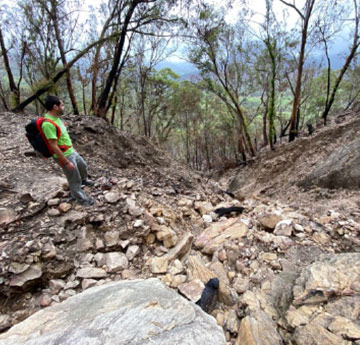 Dr Neris-Tome standing by a rocky gully