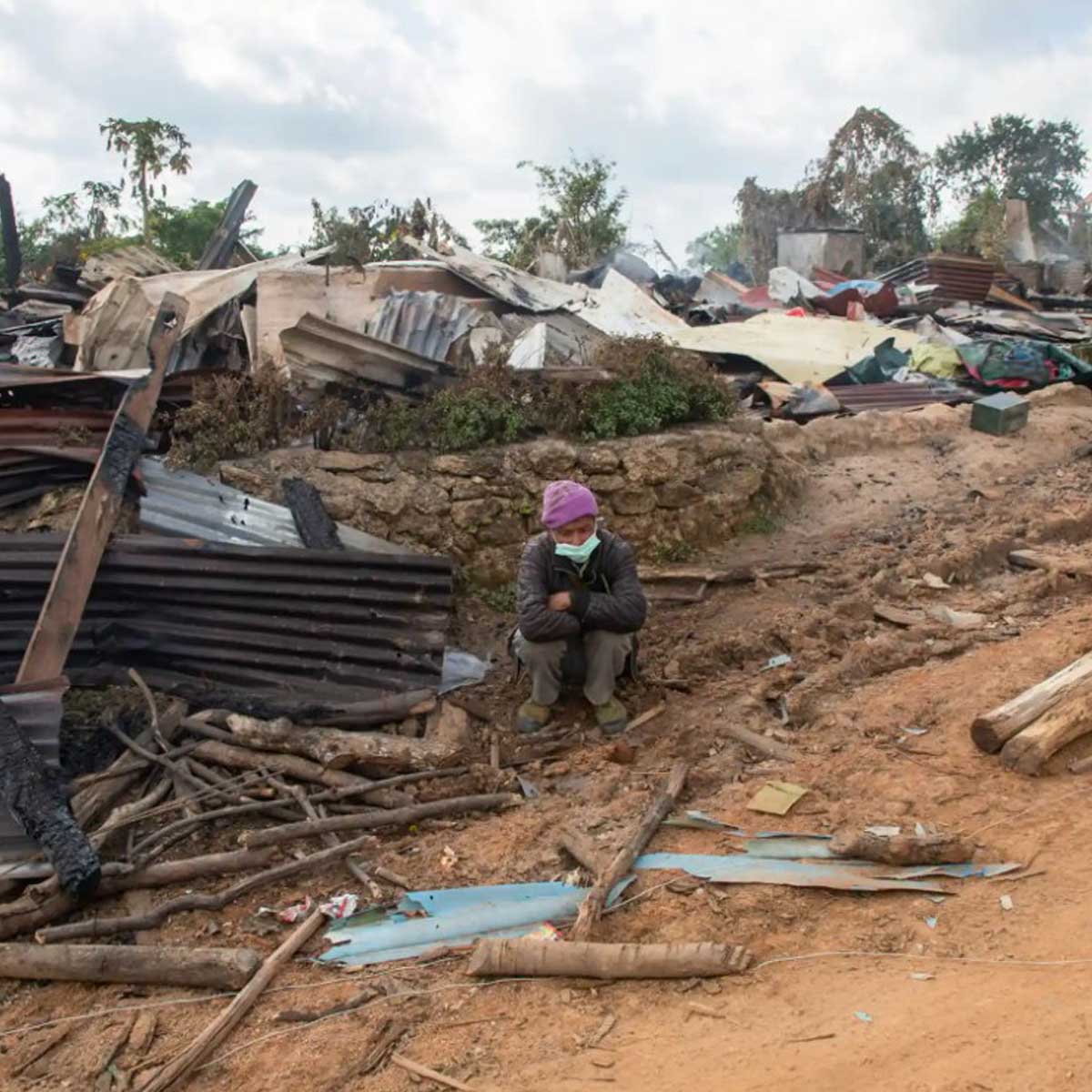 A person sitting in wreckage related to conflict