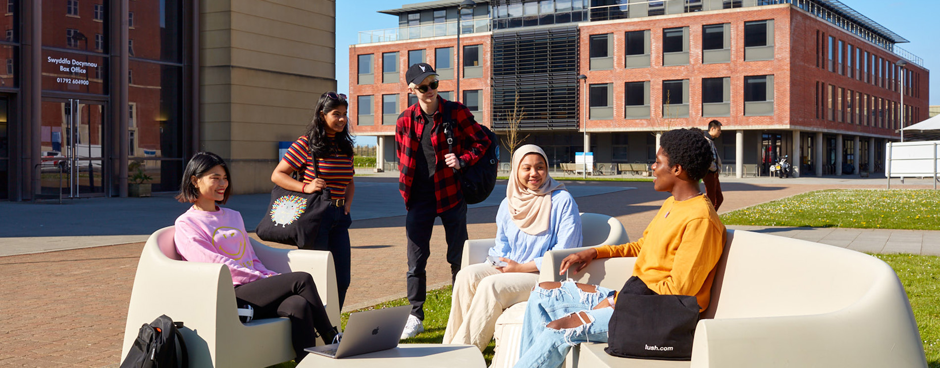 students sitting on chairs outside chatting and smiling