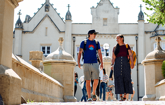 A group of students walking around Singleton Park Campus, with Singleton Abbey at the background.