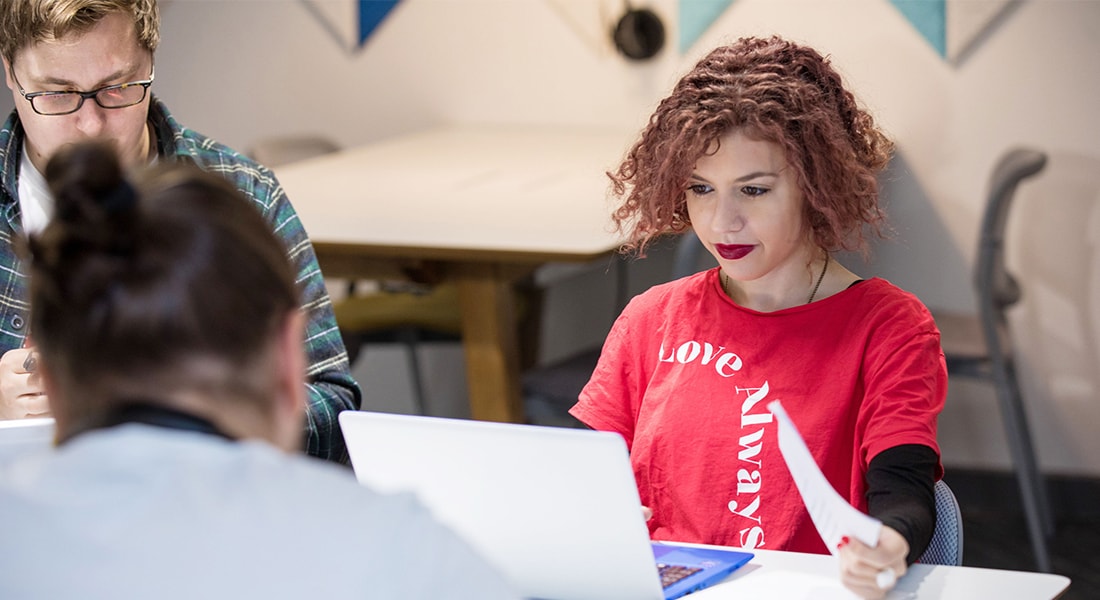 Girl in a red top working at a laptop