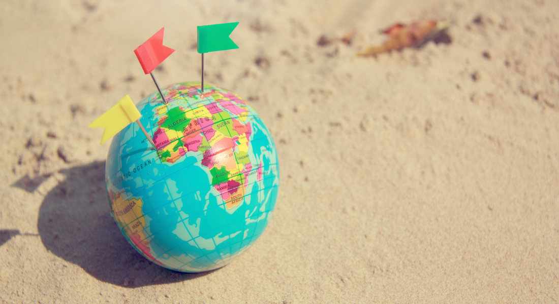 Small globe on a beach with flag markers