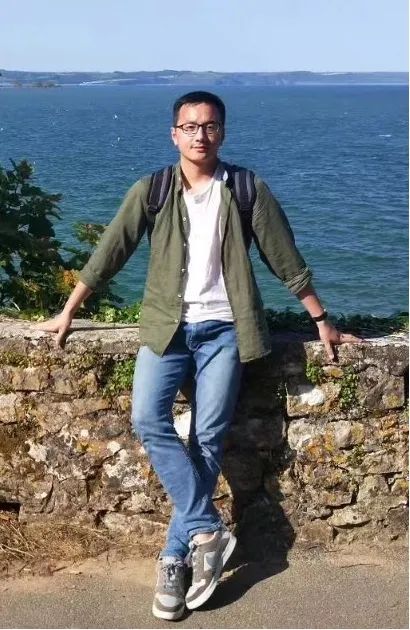 student smiling at the camera, standing in front of the sea