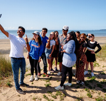 Group of students on beach smiling at the camera