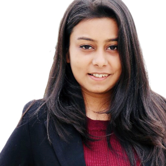 Sakshi smiling with a street of houses in the background