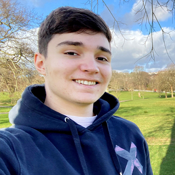 Photo of Jamie smiling in a green field