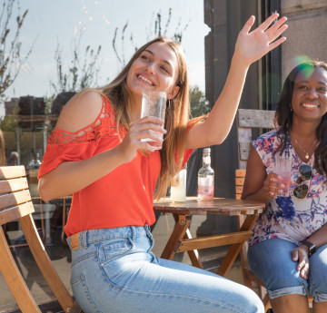 two female students having a drink in the sun.