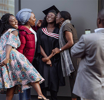 Graduate with family hugging as her parent takes a photo.